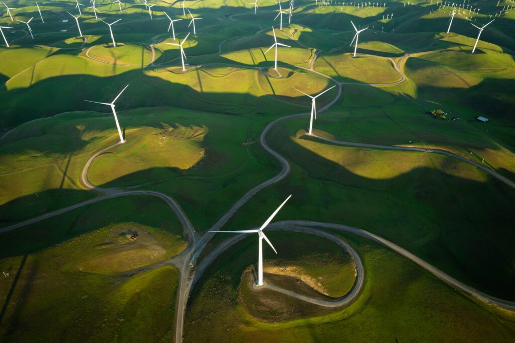 Aerial view of wind turbines across green hills for renewable energy operations