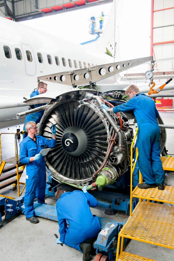 Aircraft maintenance technicians inspecting and servicing a jet engine in an aviation hangar