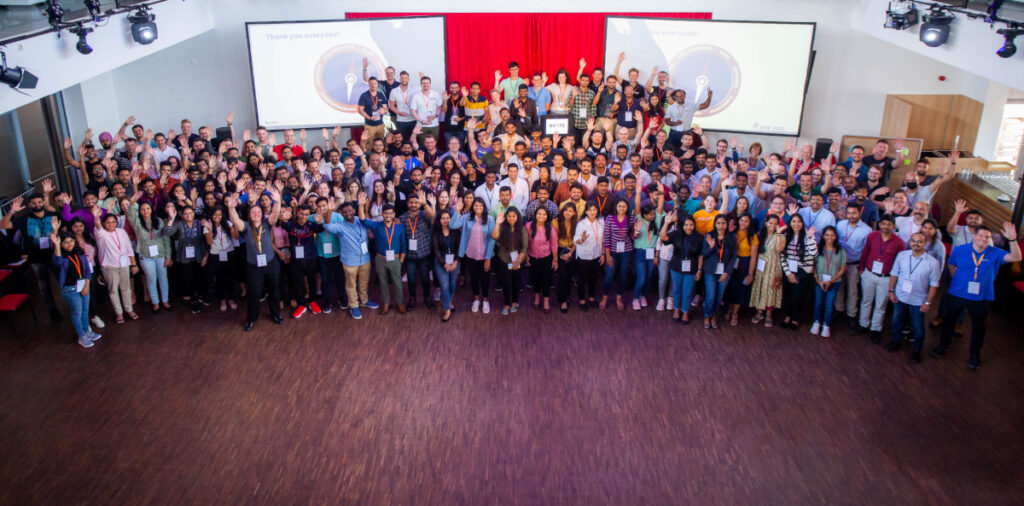 Gruppenfoto des globalen Evora-Teams bei einem Firmenevent, das Zusammenarbeit, Kultur und Kundenerfolg feiert.