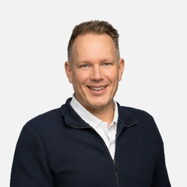 Evora team member, bas tiggelman, smiling in a navy sweater during a professional studio portrait.